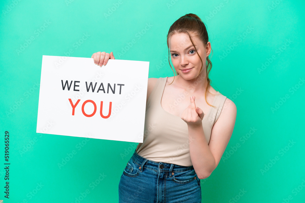 Young caucasian woman isolated on green background holding We Want You board and doing coming gesture Young caucasian woman isolated on green background holding We Want You board and doing coming gesture