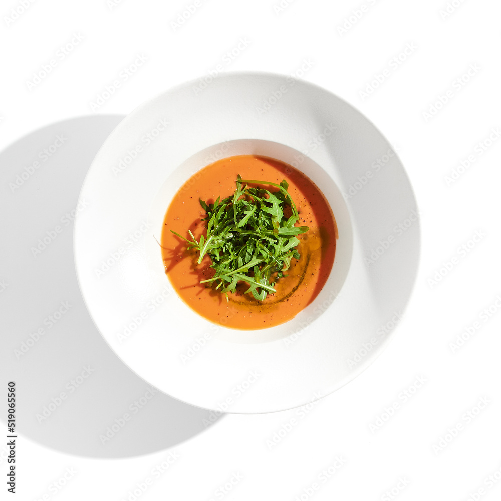 Summer Spanish soup - gazpacho with rocket salad isolated on white background. Vegetarian cold tomato soup in white plate. Meatless food in menu. Veggie lunch. Healthy food. Plant based eating. - obrazy, fototapety, plakaty 