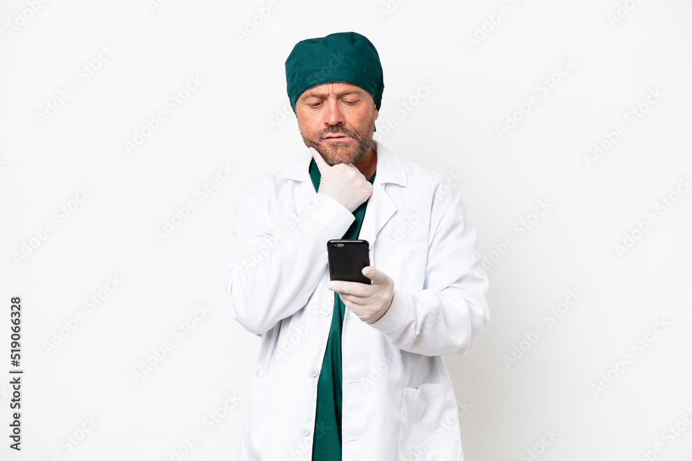 Middle age surgeon in green uniform isolated on white background thinking and sending a message Middle age surgeon in green uniform isolated on white background thinking and sending a message