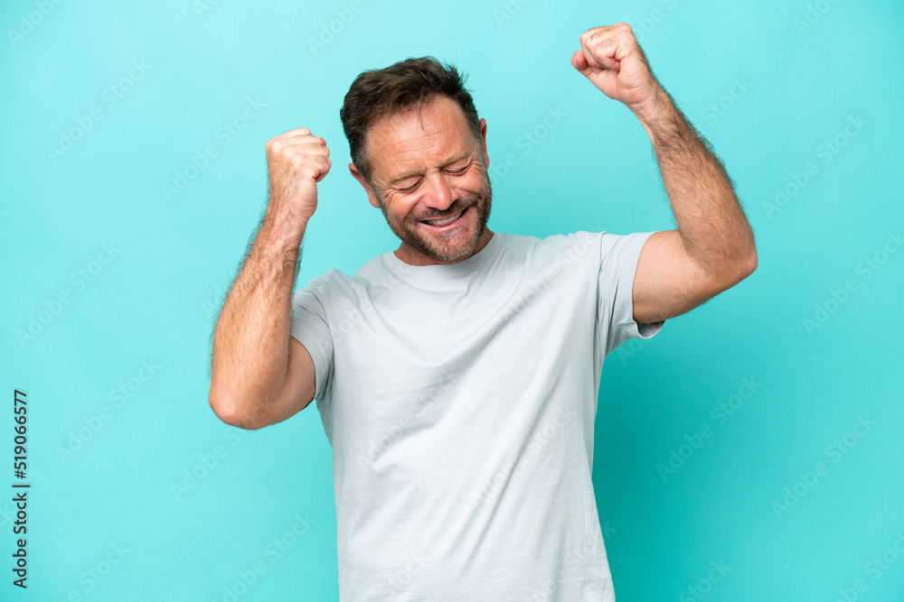 Middle age caucasian man isolated on blue background celebrating a victory