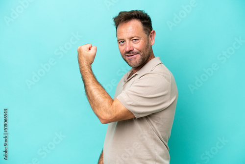 Middle age caucasian man isolated on blue background doing strong gesture