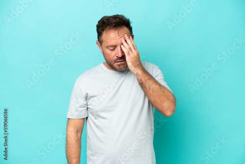 Middle age caucasian man isolated on blue background with headache