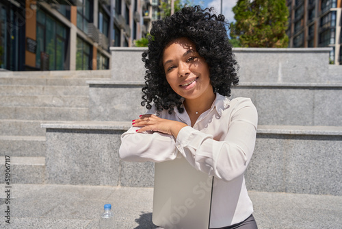 Multiracial woman sitting on stairs while walking in city