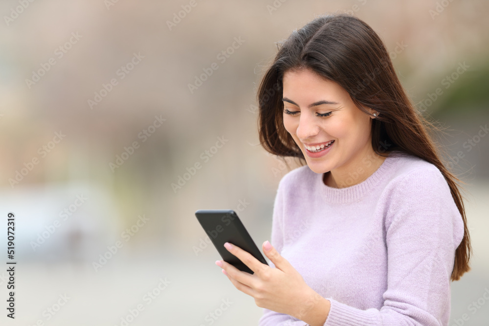 Happy teen checking smart phone in the street Happy teen checking smart phone in the street