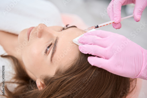 Syringe is injected subcutaneously on the forehead of lady