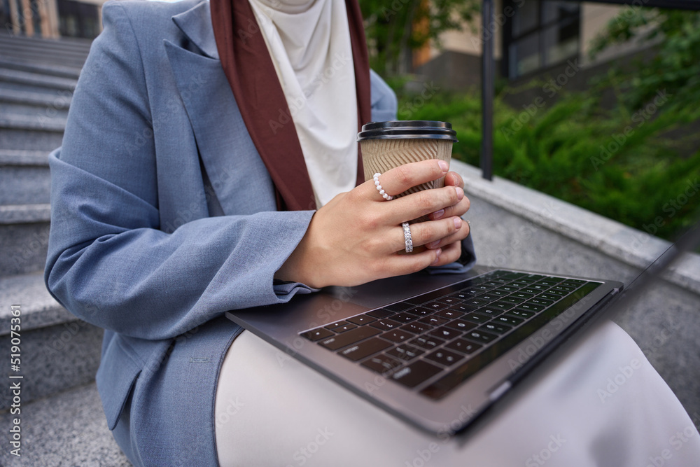Woman in hijab with laptop and coffee Woman in hijab with laptop and coffee