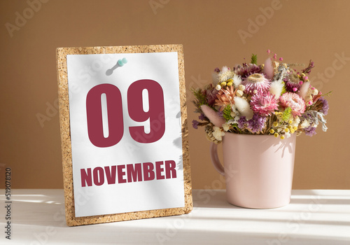 november 9. 9th day of month, calendar date.Bouquet of dead wood in pink mug on desktop.Cork board with calendar sheet on white-beige background. Concept of day of year, time planner, autumn month photo