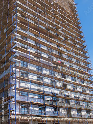 Construction of a new high-rise residential building in scaffolding and protective mesh