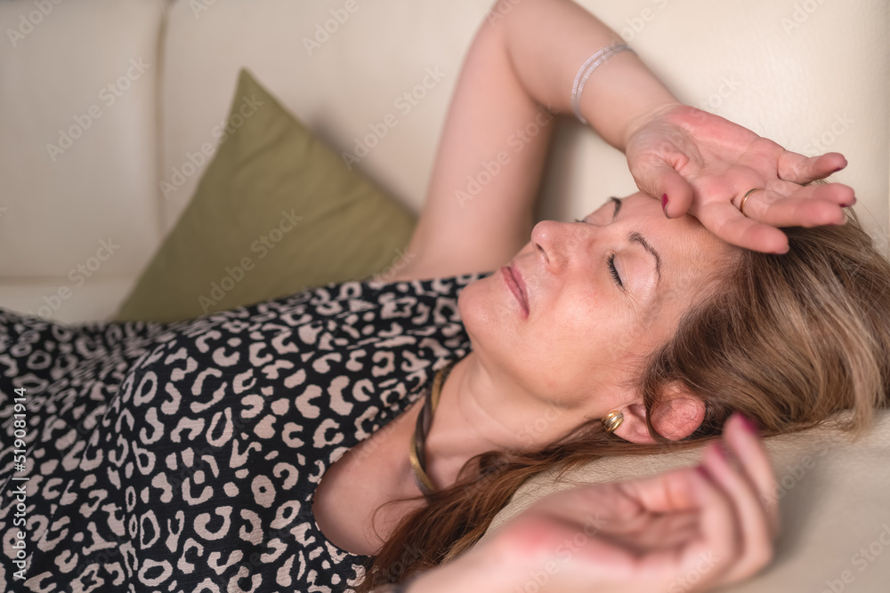 Woman lying on the sofa in a lot of heat due to the hormonal disorder of menopause.
