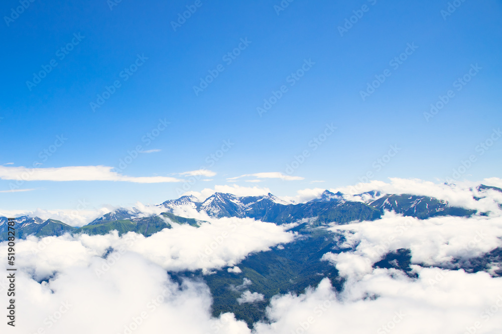 mountain peaks above the clouds on a sunny summer day