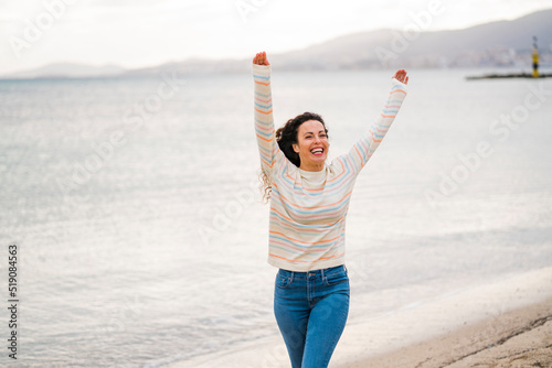 Happy woman with arms raised walking on beach
