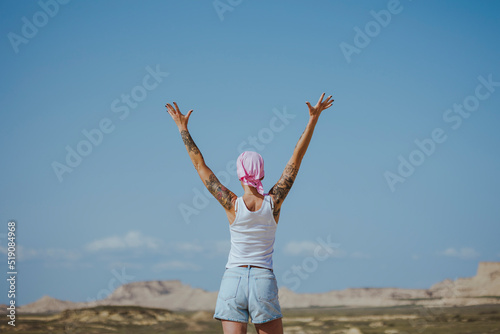 Woman with arms raised standing in Bardenas desert, Spain photo