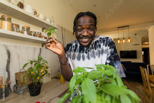 Happy man holding basil leaves in kitchen photo