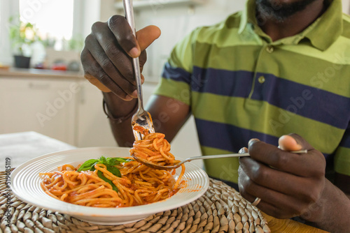 Hands of man holding fork with spaghetti at home photo