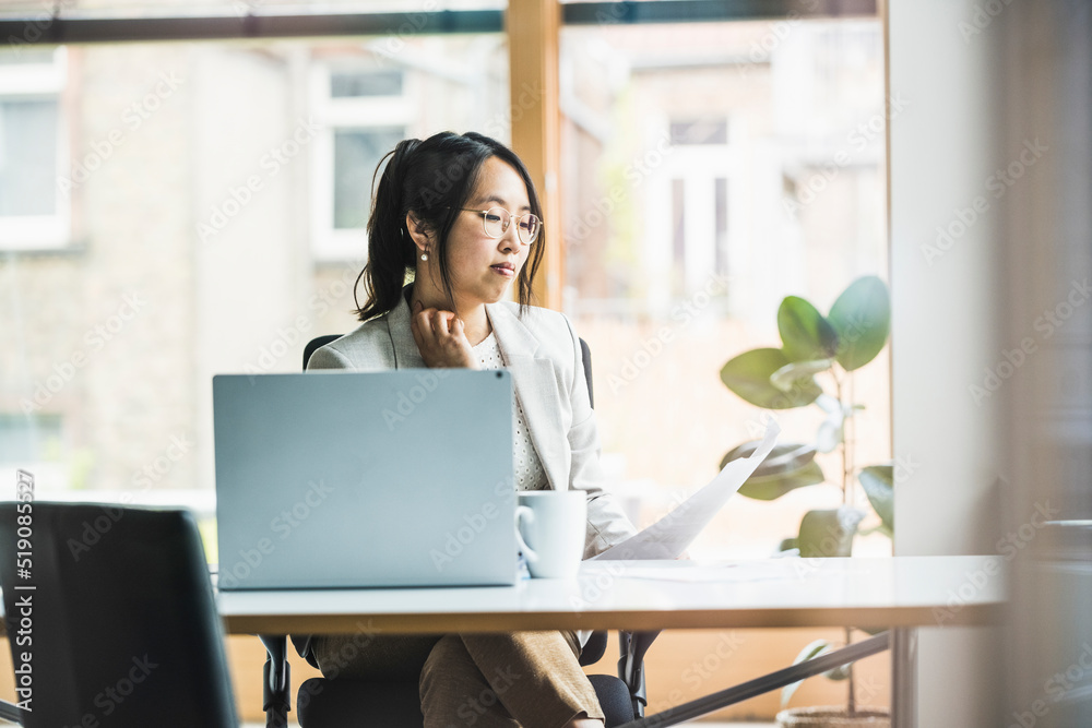 Businesswoman with eyeglasses reading document at desk Businesswoman with eyeglasses reading document at desk