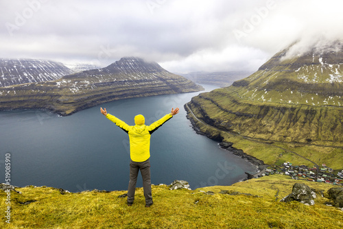Faroe Islands, Eysturoy, Funningur, Hiker standing with raised arms at edge of Hvithamar vantage point