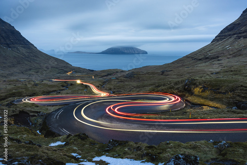 Faroe Islands, Streymoy, Vehicle light trails stretching along remote winding road photo