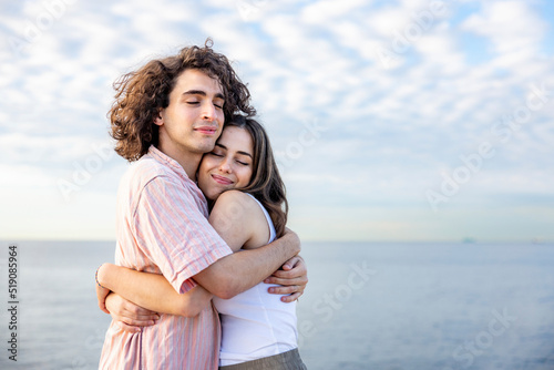 Happy young couple with eyes closed embracing each other