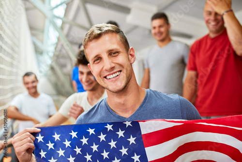 Happy man holding American Flag with by friends at sports event in stadium photo