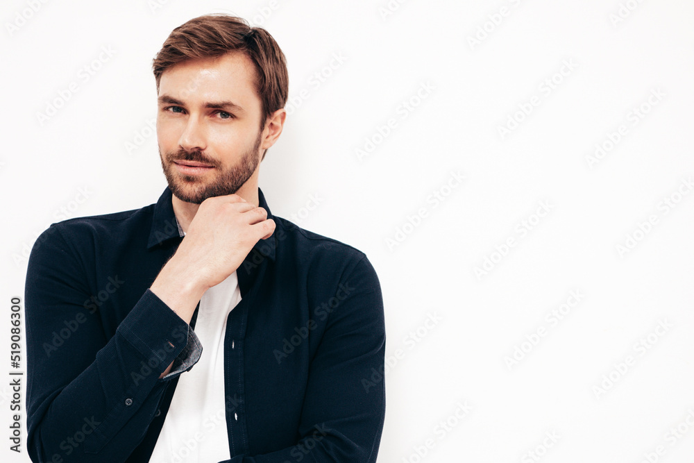 Closeup portrait of handsome smiling model. Sexy stylish man dressed in shirt and jeans. Fashion hipster male posing near white wall in studio. Isolated Closeup portrait of handsome smiling model. Sexy stylish man dressed in shirt and jeans. Fashion hipster male posing near white wall in studio. Isolated