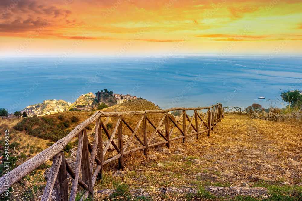 mountain landscape with a hiking trail leading to a mountain town and beautiful blue seashore far away