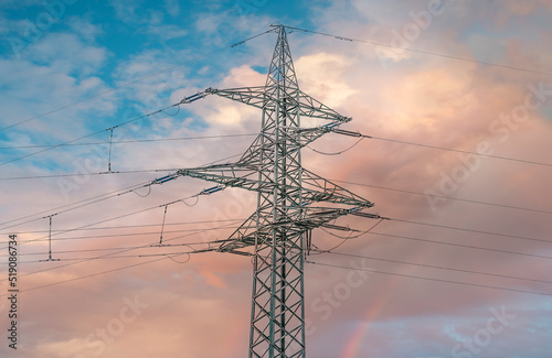 Power grid high voltage pylon against blue cloudy sky. Power supply, power distribution, power transmission, power transmission, high voltage power supply.