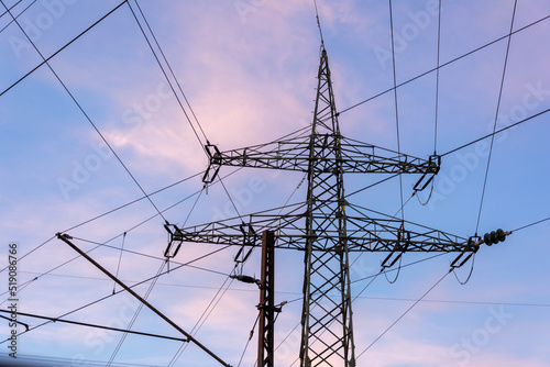 Power grid high voltage pylon against blue cloudy sky. Power supply, power distribution, power transmission, power transmission, high voltage power supply.