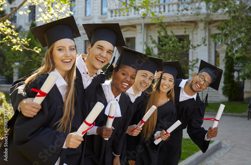 Wallpaper Mural Happy multiracial people college graduates in academic gown and hats posing with smile after graduation ceremony with certificates in their hands standing near university campus. Higher education Torontodigital.ca