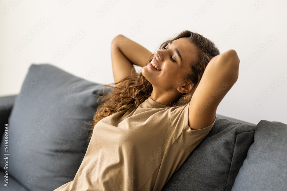 Happy young woman lying on couch and relaxing at home Happy young woman lying on couch and relaxing at home