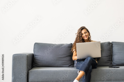 Attractive young woman using laptop while sitting on a couch at home © dianagrytsku