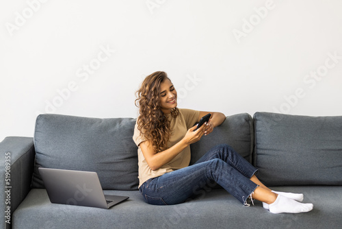 Portrait beautiful young woman use smart mobile phone on sofa in living room interior
