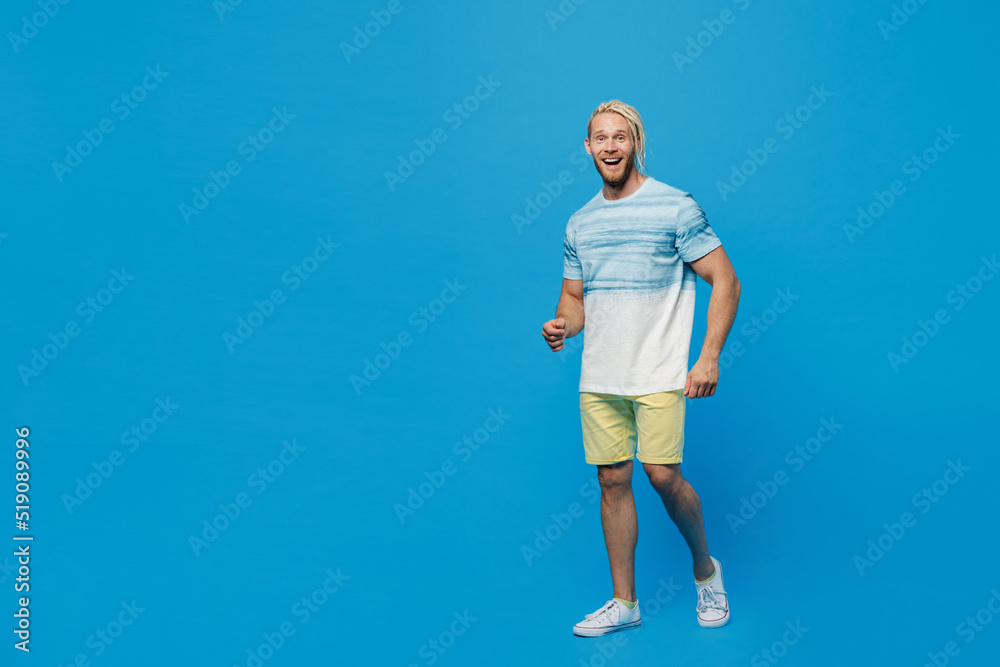 Full body smiling young blond man with dreadlocks 20s he wear white t-shirt look camera walking going strolling isolated on plain pastel light blue background studio portrait People lifestyle concept Full body smiling young blond man with dreadlocks 20s he wear white t-shirt look camera walking going strolling isolated on plain pastel light blue background studio portrait People lifestyle concept