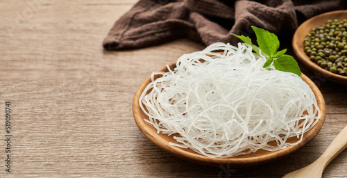 Asian vermicelli or cellophane noodle and mung green bean in wooden plate on wood table background. glass noodle                       photo