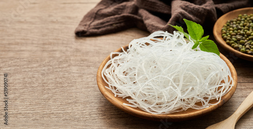 Asian vermicelli or cellophane noodle and mung green bean in wooden plate on wood table background. glass noodle                      