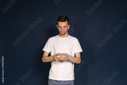 A man in a white T-shirt with Treacher Syndrome is holding a phone photo