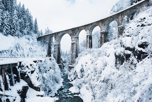 Mountain landscape with Sainte Marie bridge covered with snow in Les Houches, Chamonix valley, Eastern France. Viaduct bridge built to carry a railway over water.