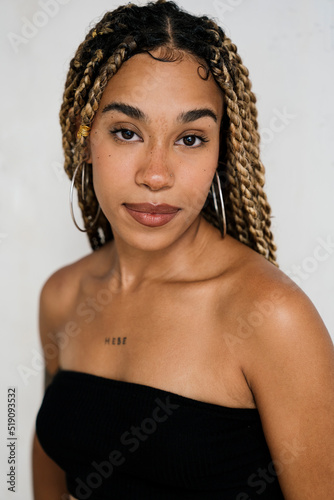 portrait of a multiracial girl smiling at camera with long blonde braids and tattoos. natural light.