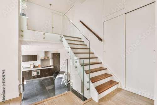 White hallway with wooden stairway leading to second floor of modern luxury apartment with minimalist interior design photo