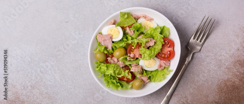 Healthy tuna salad with fresh lettuce, cherry tomatoes, quail eggs and olives in bowl