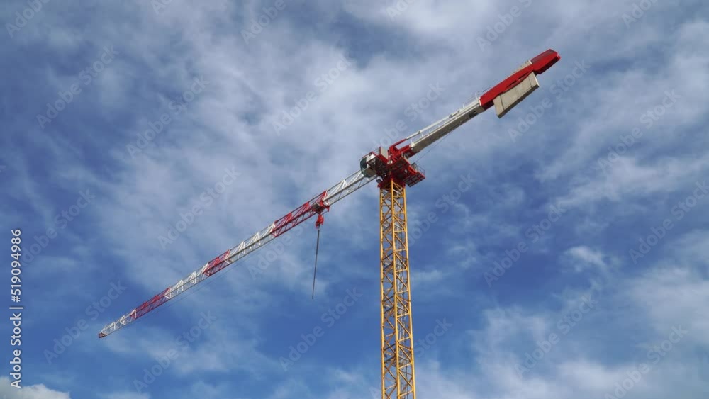 View of a modern tower crane on blue cloudy sky background View of a modern tower crane on blue cloudy sky background