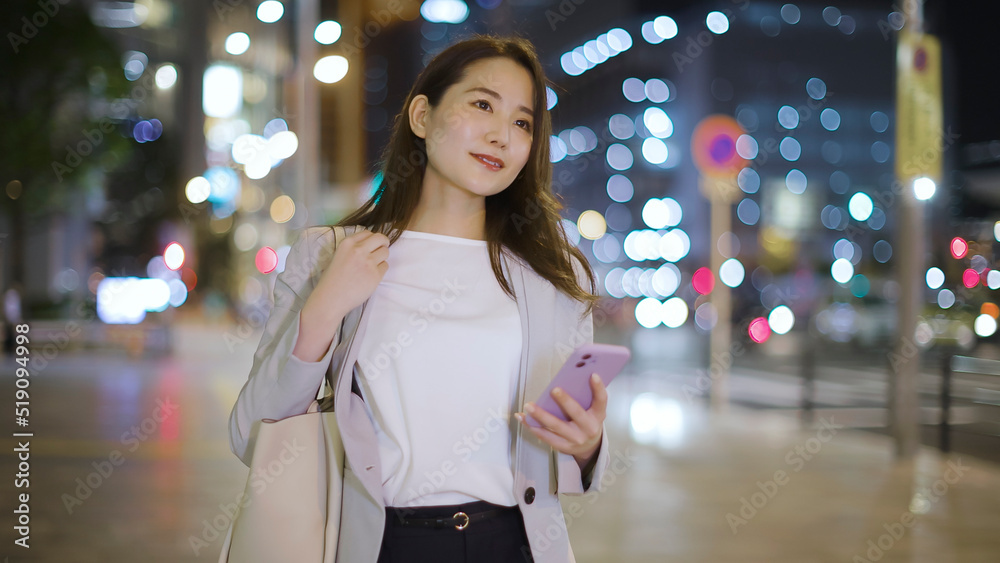Fototapeta premium 会社帰りにスマホを見るビジネスウーマン