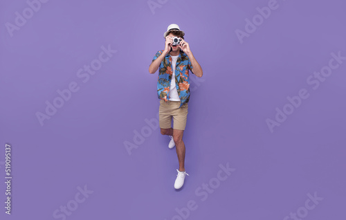 jumping photographer man is taking images photo with dslr camera isolated studio purple background. © NaMong Productions
