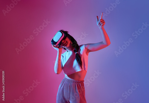 Amazed young woman using a virtual reality headset playing video games trying to touch something with hand. © NaMong Productions