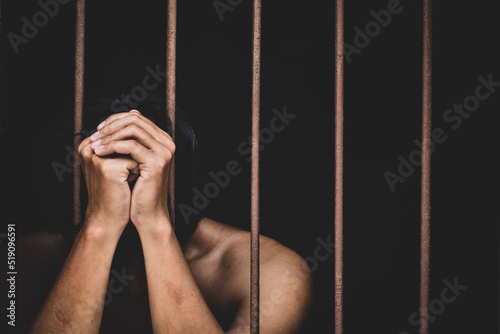 Fotografia male inmate in prison lift hand to make a wish and pray on black background