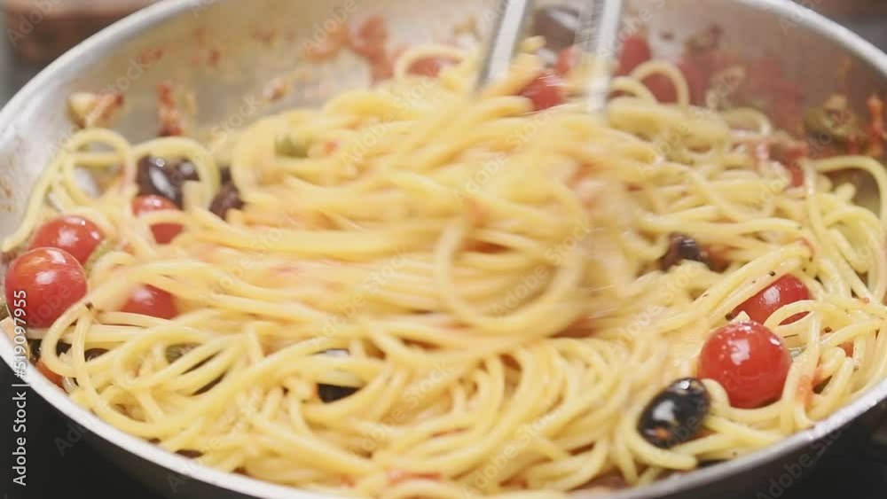 Cooking and stirring spaghetti in a frying pan.
Cooking and stirring spaghetti in a frying pan.