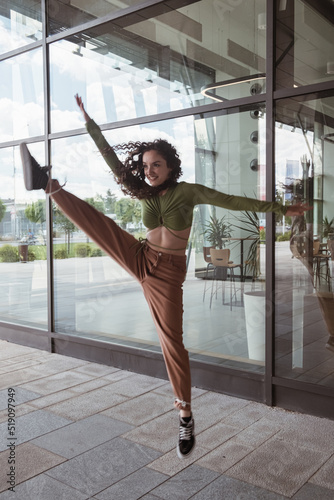 Joyful woman jumping in front of a modern building freestyle dance