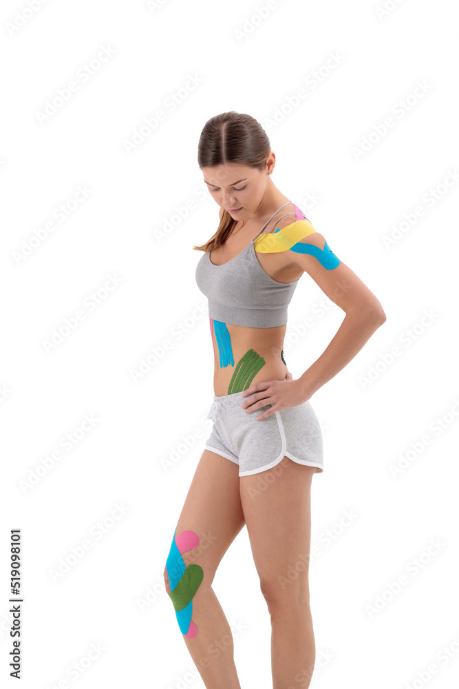 Physio tapes applied to the body of a young athletic woman isolated on white. Physiotherapy, kinesio taping, kinesiology and recovery treatment concepts. Physio tapes applied to the body of a young athletic woman isolated on white. Physiotherapy, kinesio taping, kinesiology and recovery treatment concepts.