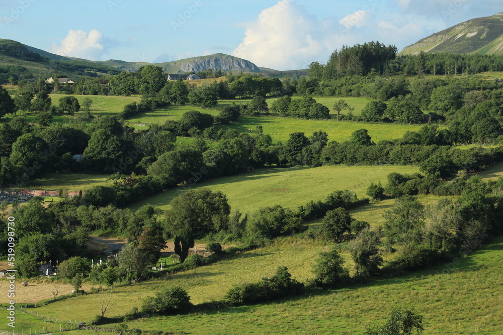 Landscape at Calry, County Sligo, Ireland featuring hill of green fields of farmland pastures bordered by trees Landscape at Calry, County Sligo, Ireland featuring hill of green fields of farmland pastures bordered by trees