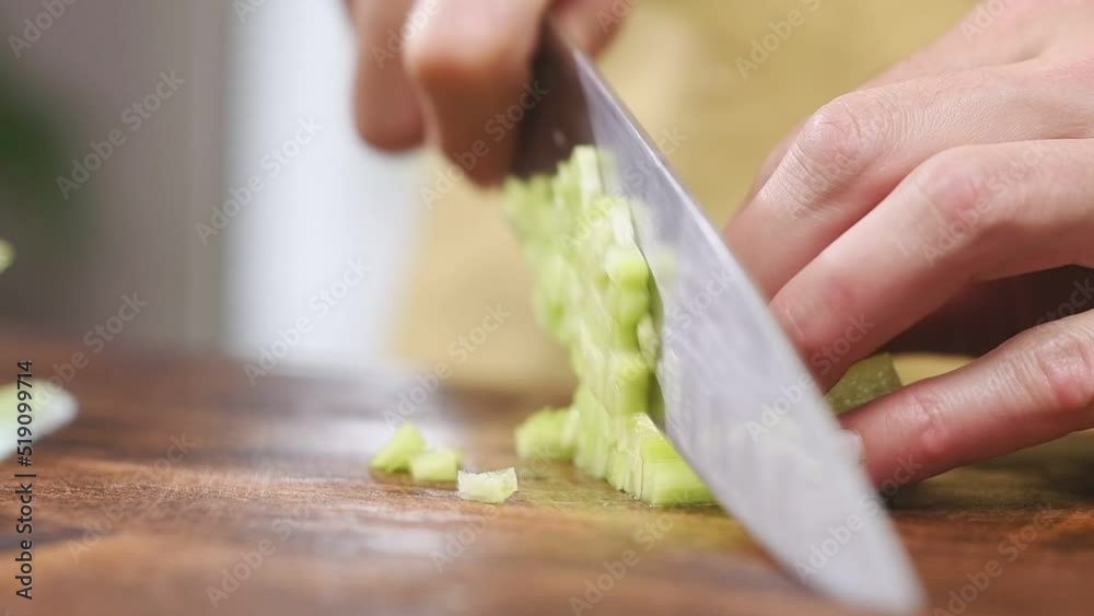 Chef cuts fresh cucumber on a wooden cutting board.
Chef cuts fresh cucumber on a wooden cutting board.
