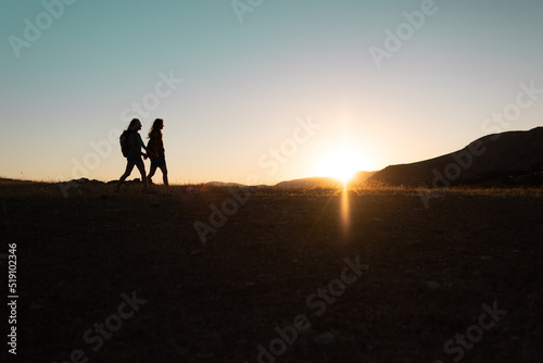 two people walk along a mountain range